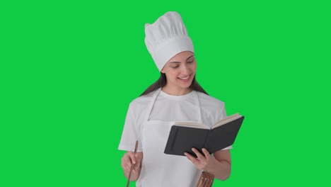 Happy-Indian-female-professional-chef-making-food-from-recipe-book-Green-screen