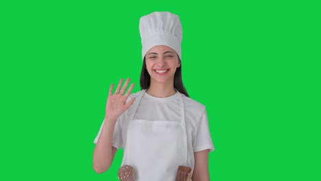 Happy-Indian-female-professional-chef-waving-Hi-to-the-camera-Green-screen