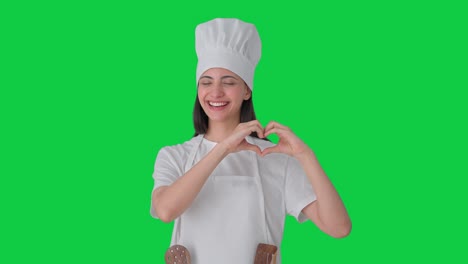Happy-Indian-female-professional-chef-making-heart-sign-Green-screen