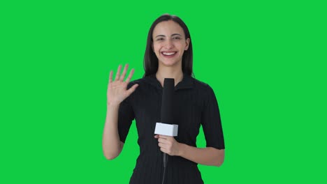 Happy-Indian-female-news-reporter-waving-Hello-Green-screen