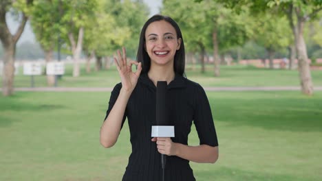 Happy-Indian-female-news-reporter-showing-okay-sign