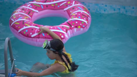 girl-plays-an-inflatable-ring-is-in-swimming-pool-in-the-garden