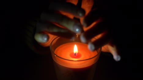 Close-up-of-woman-hand-lighting-candles-in-the-dark-night-at-home