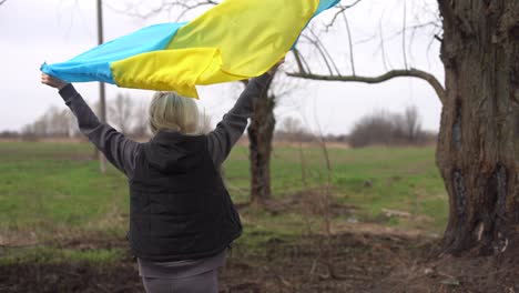 woman-flag-of-ukraine-near-burnt-tree