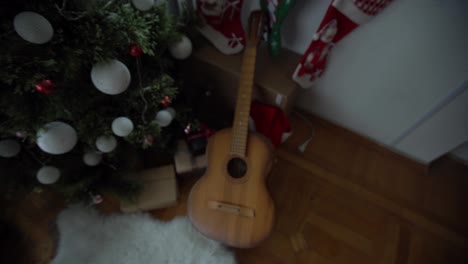 Gifts-and-presents-under-the-xmas-tree.-Christmas-tree-with-christmas-decorations-and-christmas-lights-and-guitar-on-background