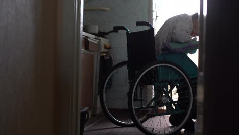 Alte-Einsame-Frau-Sitzt-In-Einem-Rollstuhl-Am-Fenster-In-Seinem-Haus