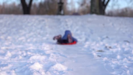 little-girl-goes-downhill-on-an-ice-sled-down-the-winter-snow-covered-hill