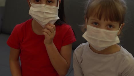 Two-little-kids-girls.-Epidemic-pandemic-coronavirus-2019-ncov-sars-covid-19-flu-virus-concept.-Point-index-finger-on-sterile-face-mask