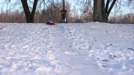 a-girl-on-a-snow-hill,-one-goes-down-on-an-ice-sled