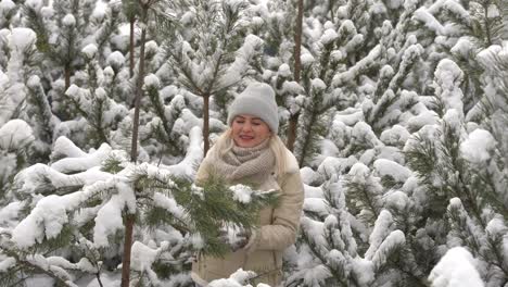 Beautiful-woman-standing-among-snowy-trees-in-winter-forest-and-enjoying-first-snow.-Woman-in-winter-woods.