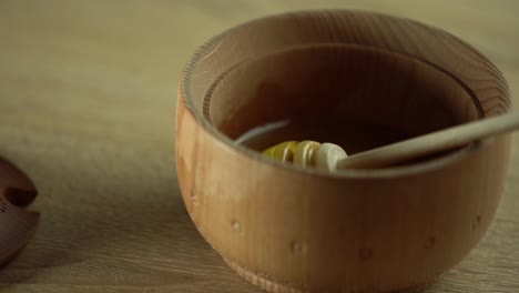 Honey-dripping,-pouring-from-honey-dipper-in-wooden-bowl.-Close-up.-Healthy-organic-Thick-honey-dipping-from-the-wooden-honey-spoon,-closeup.-4K-UHD-video-footage.-Slow-motion