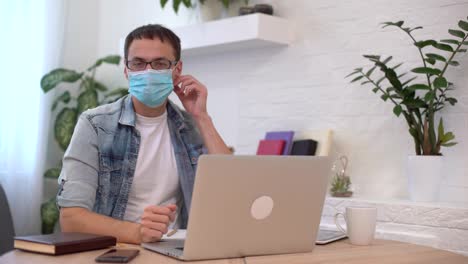 Portrait-of-young-businessman-takes-off-face-mask-at-workplace.-Safe-work-in-pandemic-time