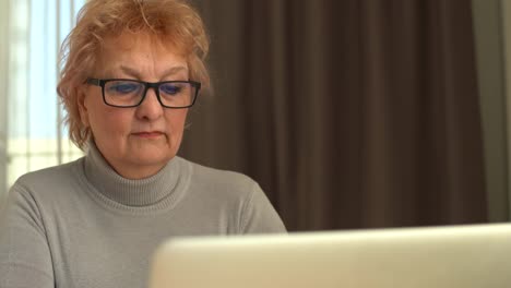 Head-shot-mature-woman-looking-at-camera-and-talking,-grandmother-chatting-with-relative-online,-making-video-call,-middle-aged-blogger-recording-vlog,-teacher-speaking-to-webcam,-distance-lecture