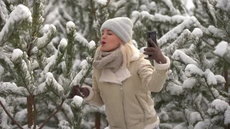 A-girl-in-white-clothes-stands-near-a-pine-tree-in-the-snow.