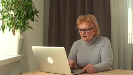 Head-shot-mature-woman-looking-at-camera-and-talking,-grandmother-chatting-with-relative-online,-making-video-call,-middle-aged-blogger-recording-vlog,-teacher-speaking-to-webcam,-distance-lecture