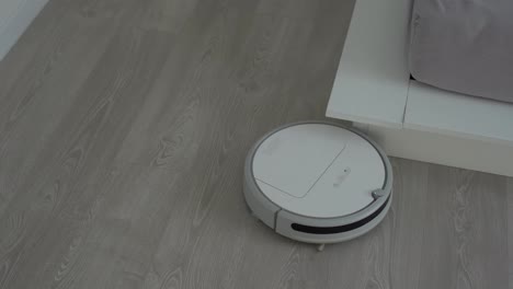 Weißer-Roboterstaubsauger-Auf-Laminatboden,-Der-Staub-Im-Wohnzimmer-Reinigt.-Intelligente-Housekeeping-Technologie.