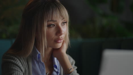 Portrait-of-a-beautiful-young-and-attractive-Asian-woman-is-sitting-and-looks-worried-and-serious-as-she-broods-in-front-of-her-laptop-computer-during-the-day.
