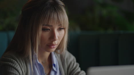 An-Asian-woman-sits-brooding-and-looks-at-a-laptop-screen.-Brainstorm-and-anxious-on-his-face.-Brooding-Asian-woman