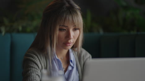 Young-Beautiful-smiling-Asian-business-woman-holding-a-coffee-and-laptop-Placed-at-the-wooden-table-at-the-office.-Woman-checking-mail-or-researching-while-telecommuting