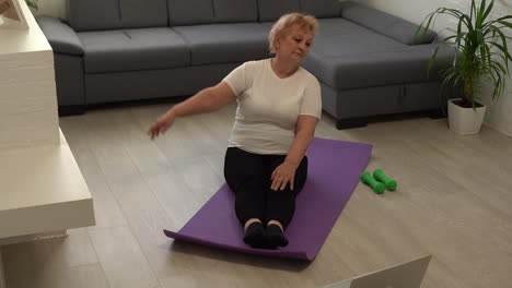 Home-Sport.-Active-Senior-Woman-Doing-Warming-Stretching-Exercises-In-Front-Of-Laptop,-Training-With-Online-Tutorials