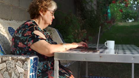 Aged-female-using-laptop-at-table-in-garden