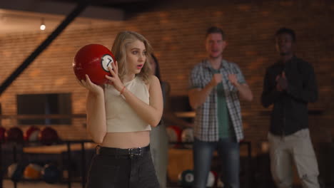 A-female-bowling-player-throws-a-ball-with-the-support-of-friends-and-rejoices-by-knocking-out-a-striking