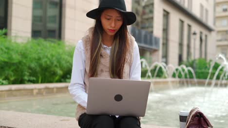 Hispanic-woman-browsing-laptop-on-street