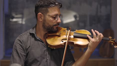 Adult-bearded-luthier-playing-hand-crafted-violin