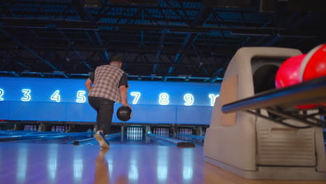The-camera-follows-one-man-throwing-a-bowling-ball-on-the-playing-track-and-jumps-rejoicing-in-the-downed-pins.-One-man-bowling-in-slow-motion