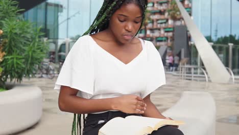 Black-woman-reading-book-on-street