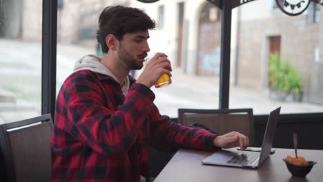 Hombre-Bebiendo-Un-Refresco-Mientras-Escribe-En-Una-Computadora-Portátil