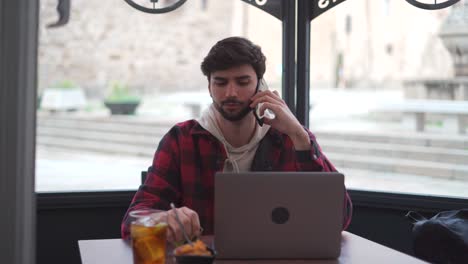 Hipster-man-speaking-on-smartphone-near-laptop