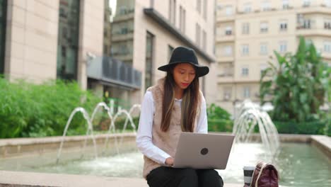 Hispanic-woman-browsing-laptop-on-street