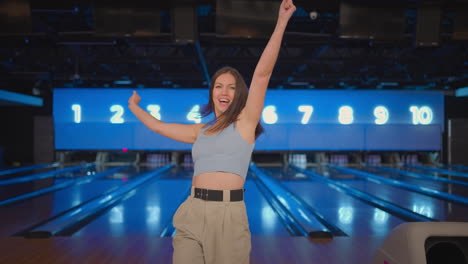 Portrait-A-Hispanic-woman-jumps-joyfully-looking-into-the-camera-celebrate-the-victory-in-slow-motion.-Throw-in-the-bowling-alley-to-make-a-shoot.-Victory-dance-and-jump-with-happiness.