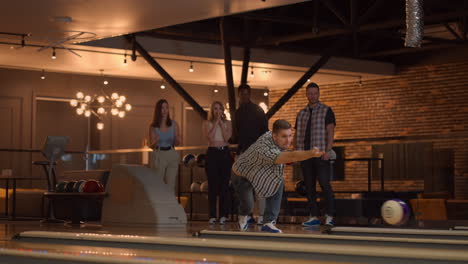 General-plan-A-young-man-in-a-shirt-bowling-player-throws-a-ball-with-the-support-of-friends-and-rejoices-by-knocking-out-a-strip