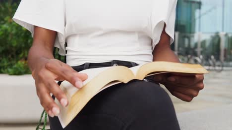 Mujer-Negra-Anónima-Leyendo-Un-Libro-En-La-Calle