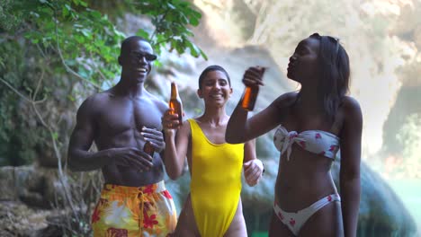 Multiracial-friends-with-beer-dancing-near-lake