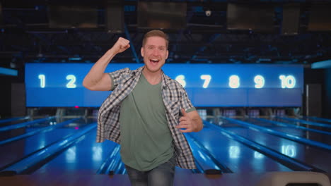 Portrait-A-young-man-jumps-joyfully-looking-into-the-camera-celebrate-the-victory-in-slow-motion.-Throw-in-the-bowling-alley-to-make-a-shoot.-Victory-dance-and-jump-with-happiness.