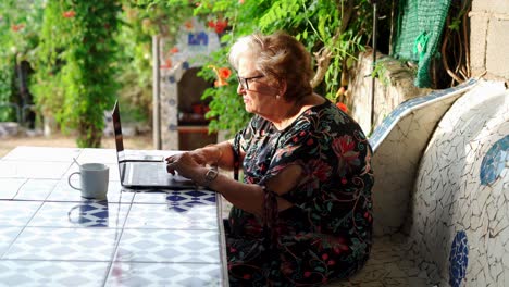 Aged-female-using-laptop-at-table-in-garden