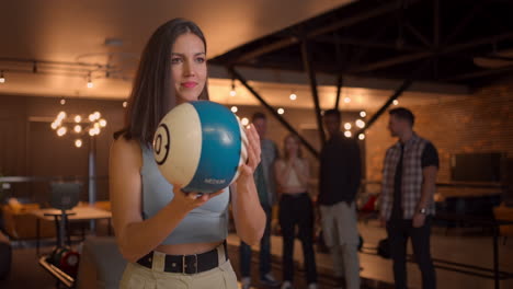 Multi-ethnic-Group-of-friends-in-a-bowling-club-Portrait-of-a-brunette-woman-throws-a-ball-and-knocks-out-a-strike