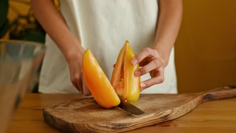 Crop-cook-cutting-yellow-bell-pepper-on-wooden-board