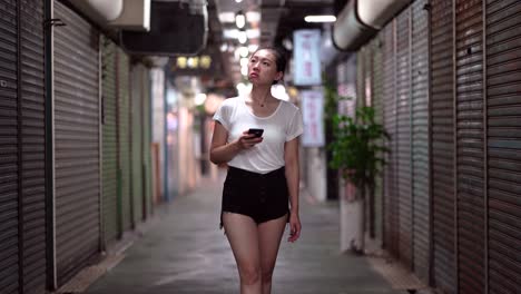 Ethnic-woman-with-smartphone-walking-on-underground-passage