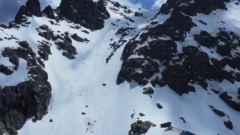 People-freeriding-down-rocky-slope-of-snowy-mountain