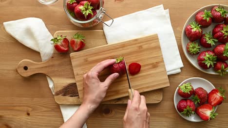 Crop-anonymous-woman-slicing-fresh-strawberries-on-cutting-board