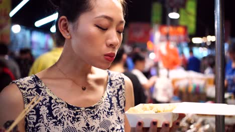 Mujer-Asiática-Comiendo-Albóndigas-Fritas-En-El-Mercado-Nocturno