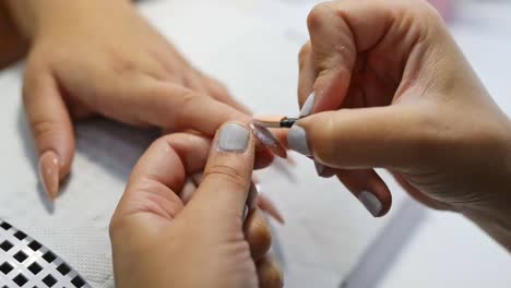 Nail-artist-applying-glitter-polish-in-salon