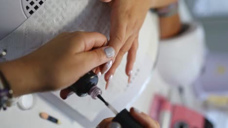 Nail-artist-applying-polish-in-salon