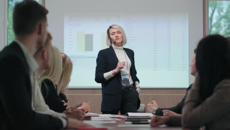 audience-is-applauding-female-business-coach-charismatic-woman-is-standing-against-charts
