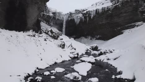 Powerful-waterfall-streaming-in-rocky-snowy-ravine-in-winter