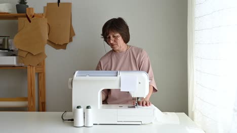 Dressmaker-sewing-on-machine-in-atelier